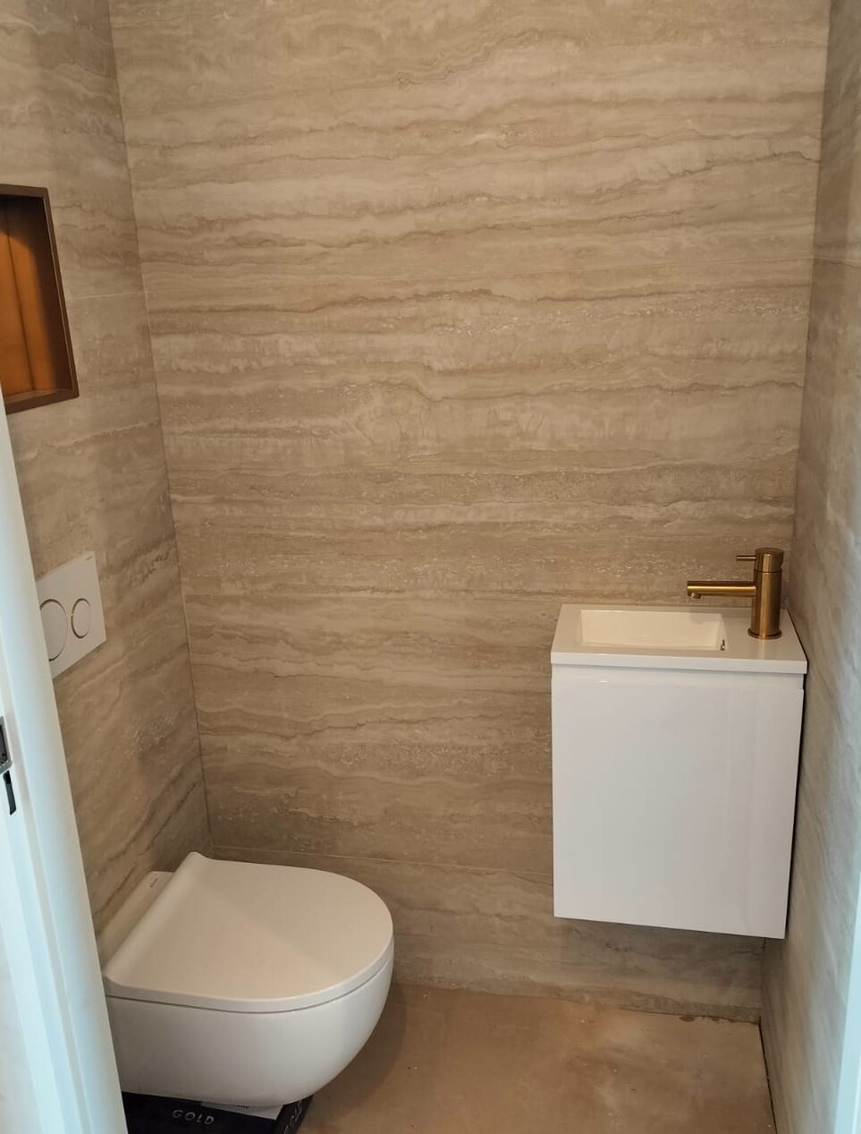 Toiletrenovatie met natuursteenlook tegels en gouden kraan in Veenendaal